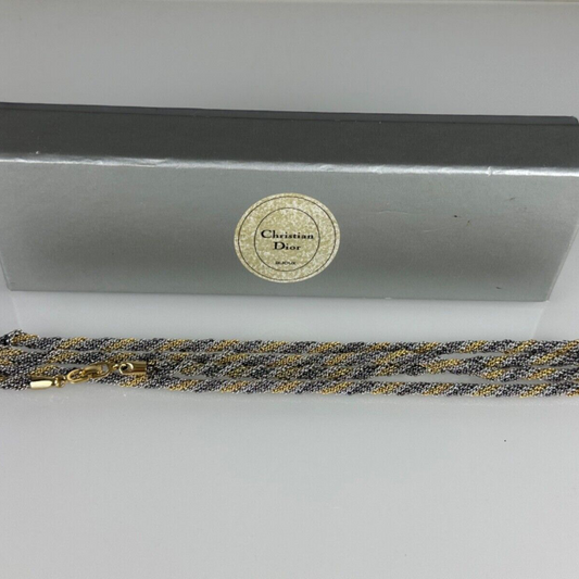 A vintage Christian Dior necklace with gold and silver colors, displayed alongside its original box.