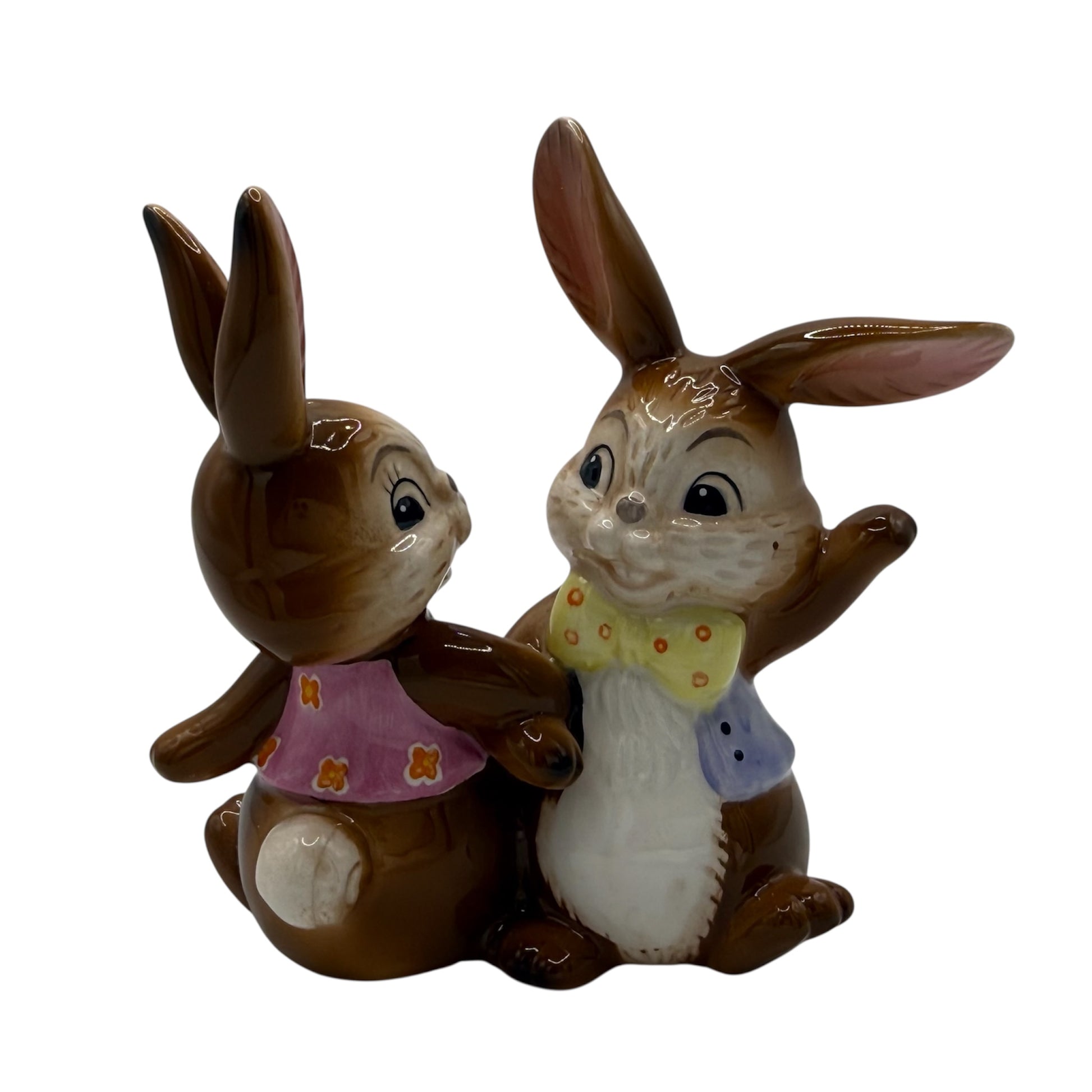 Two ceramic rabbit figurines with clothing on a white background