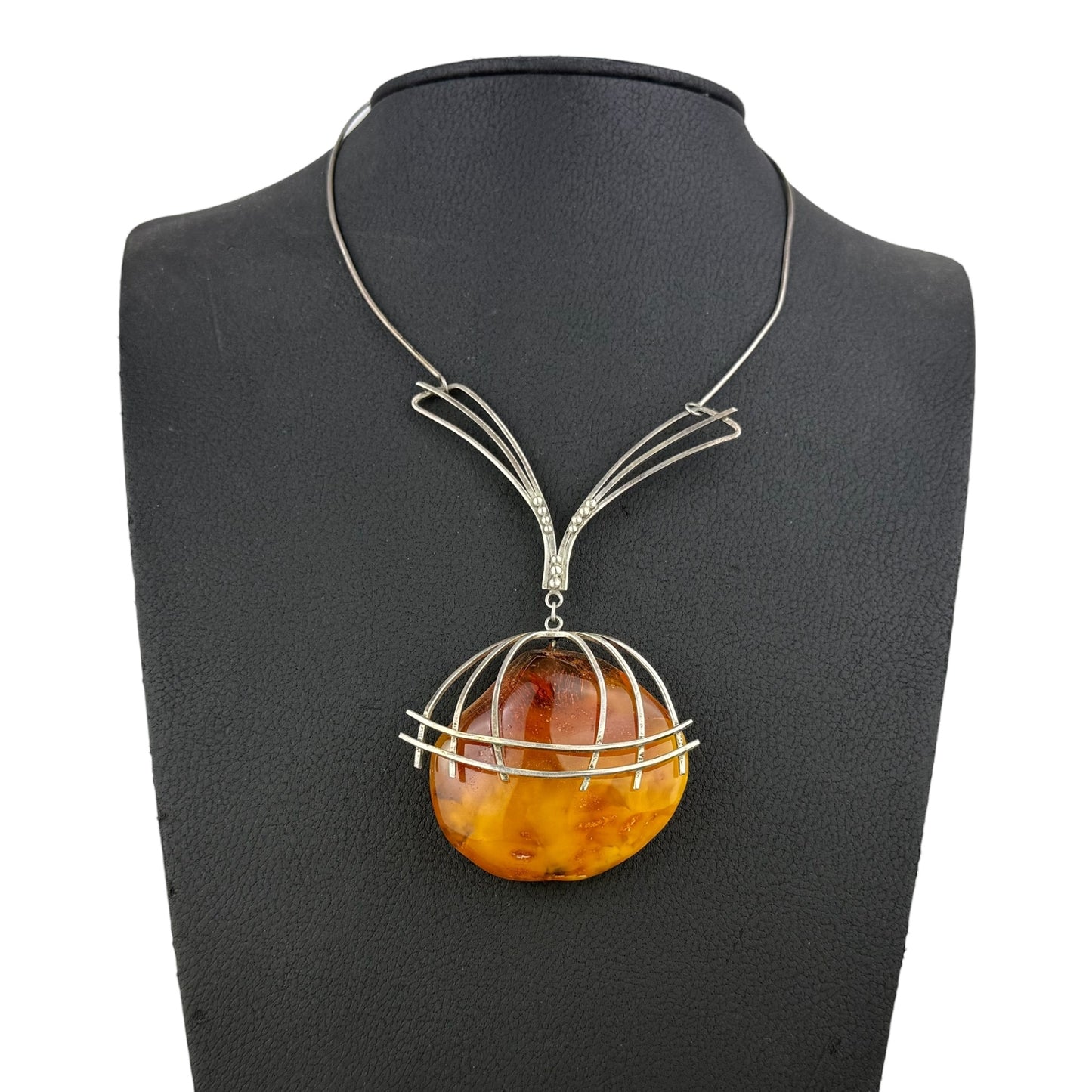 Necklace with a round amber pendant on a black mannequin bust