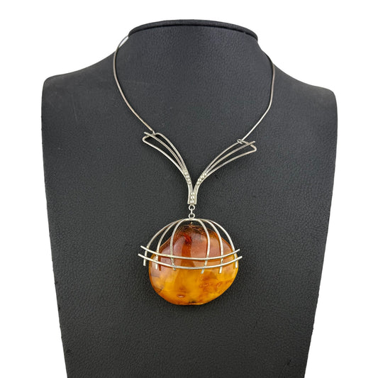 Necklace with a round amber pendant on a black mannequin bust