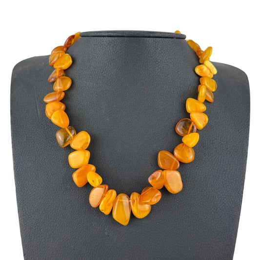 Necklace with orange beads on a gray mannequin