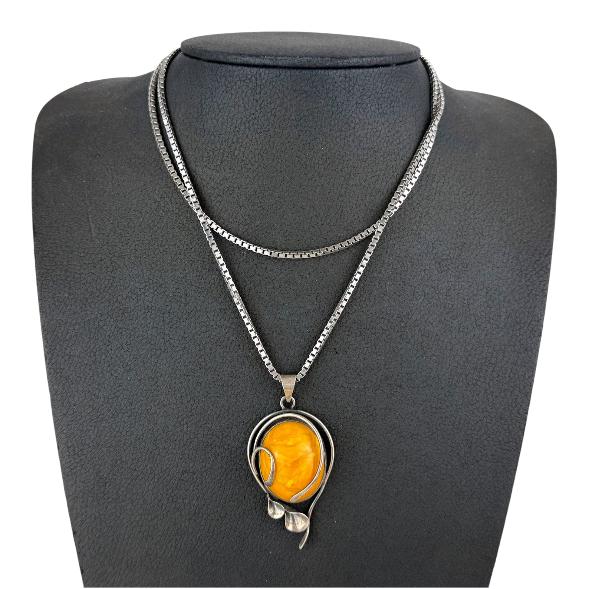 Necklace with a yellow pendant on a gray mannequin bust