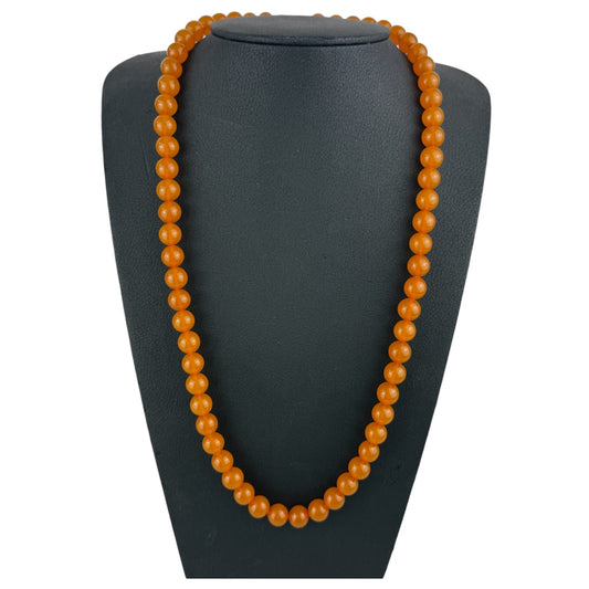 Orange beaded necklace on a black mannequin bust
