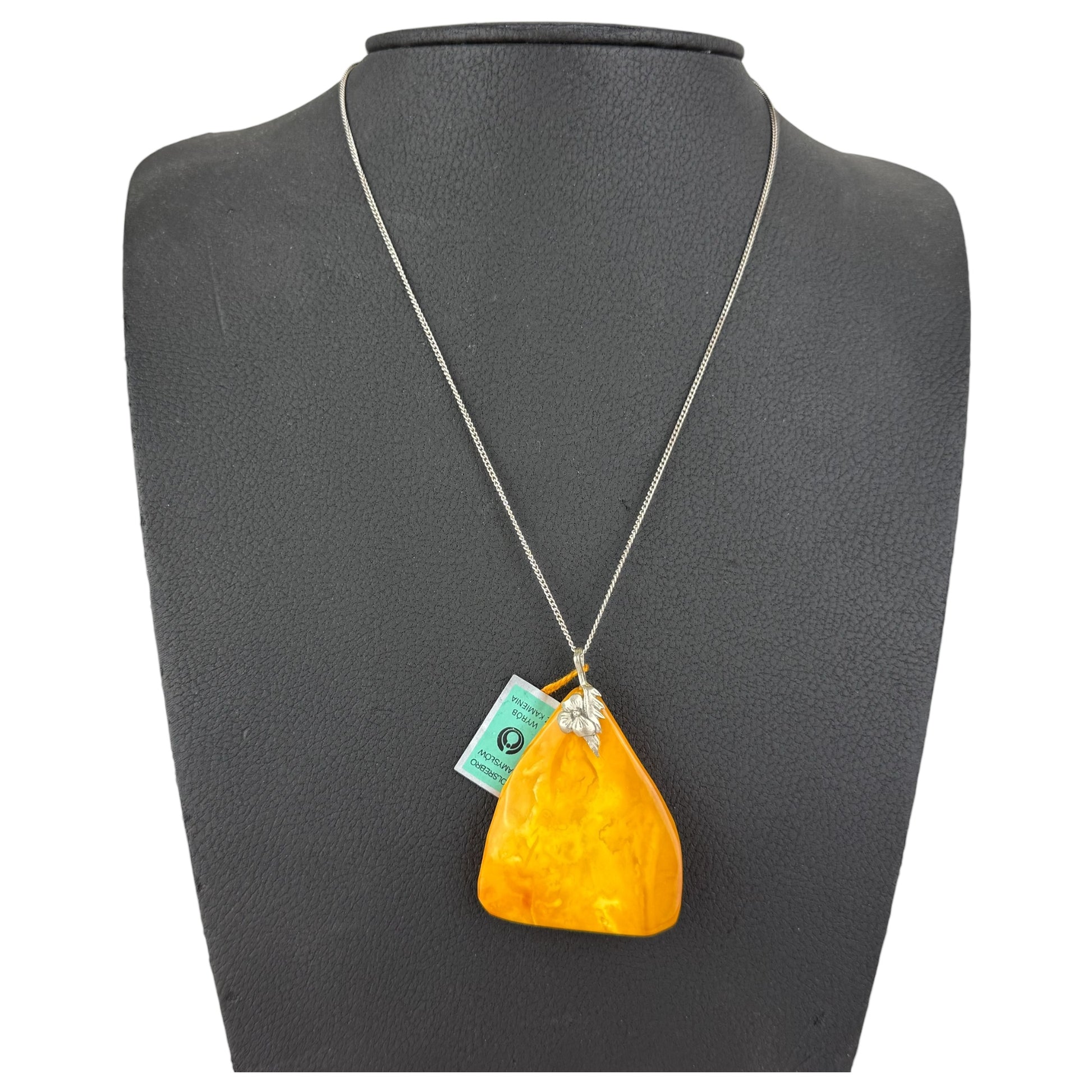 Necklace with a large orange pendant on a gray mannequin bust.
