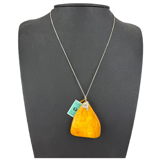 Necklace with a large orange pendant on a gray mannequin bust.